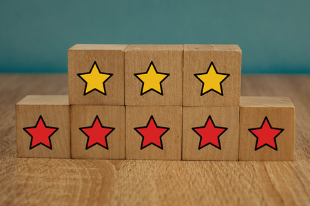 star icon yellow and red on wooden cubes far from blue background.の写真素材
