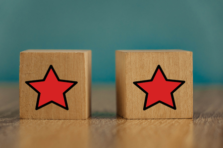 Red stars on wooden cubes on a blue background. Stars mean assessing quality. five-point rating systemの写真素材