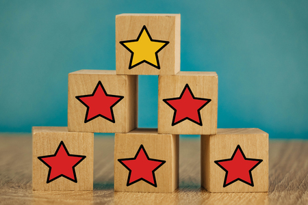star icon yellow and red on wooden cubes far from blue background.の写真素材