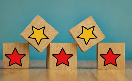 star icon yellow and red on wooden cubes far from blue background.の写真素材