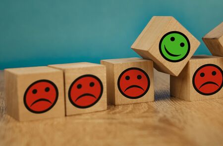 smiling and sad emoticons on a blue background. satisfaction concept.の写真素材