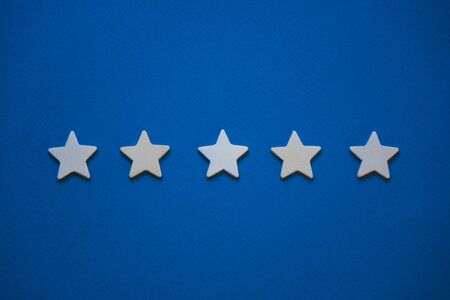 Wooden cubes in the form of stars arranged in a row on a blue background.の写真素材