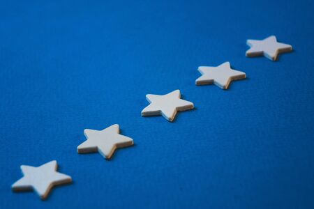 Wooden cubes in the form of stars arranged in a row on a blue background.