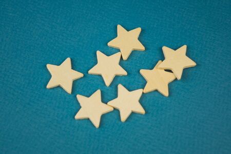 A bunch of wooden stars on a blue background chaotically scatteredの写真素材