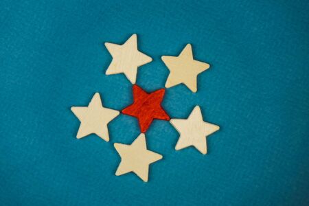 a bunch of wooden stars and one of them is highlighted in red. subject on blue background.の写真素材