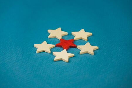 a bunch of wooden stars and one of them is highlighted in red. subject on blue background.の写真素材