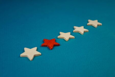a bunch of wooden stars and one of them is highlighted in red. subject on blue background.の写真素材