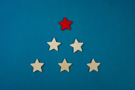 a bunch of wooden stars and one of them is highlighted in red. subject on blue backgroundの写真素材