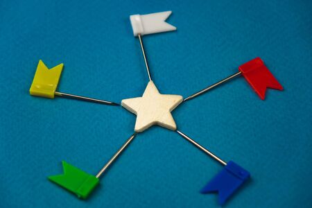 wooden star in the center and around different color flags on a blue background.