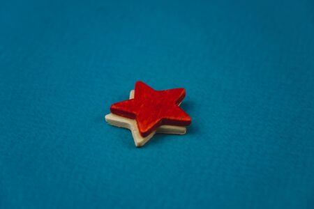 a bunch of wooden stars and one of them is highlighted in red. subject on blue backgroundの写真素材