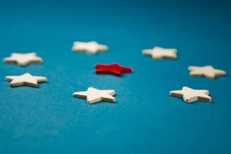 a bunch of wooden stars and one of them is highlighted in red. subject on blue background