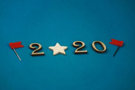 2020 number from wooden numbers on a blue background with scattered stars gears and flags around.