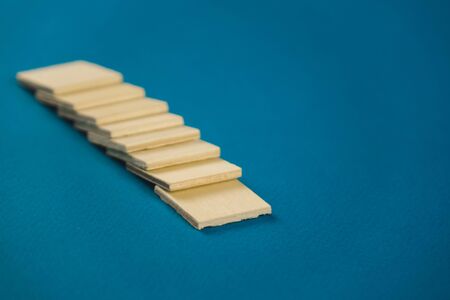 standing on top of each other small wooden blocks on a blue background.の写真素材