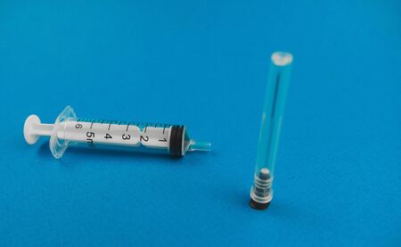 medical syringe with a needle lying on a blue background.の写真素材