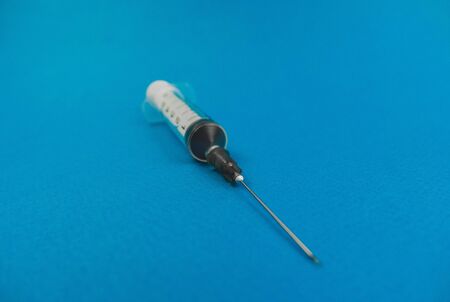 medical syringe with a needle lying on a blue background.の写真素材