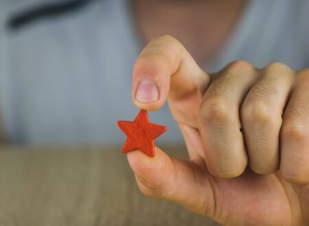 man's hand holding a red star.