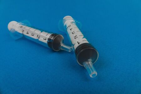 two medical syringes lying on a blue background.の写真素材