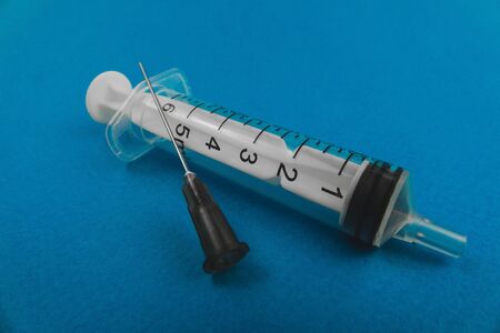medical syringe with a needle lying on a blue background.の写真素材