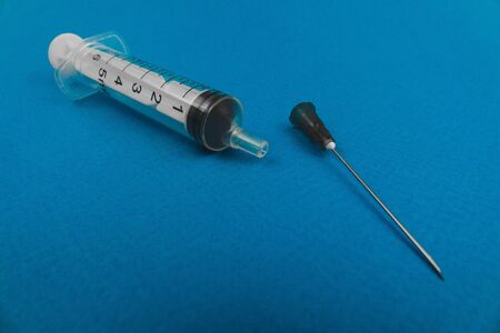 medical syringe with a needle lying on a blue background.の写真素材