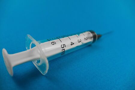 medical syringe with a needle lying on a blue background.の写真素材