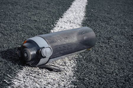 plastic bottle of water lying on grass soccer field