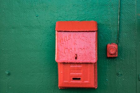 Red mailbox with green wood background close up