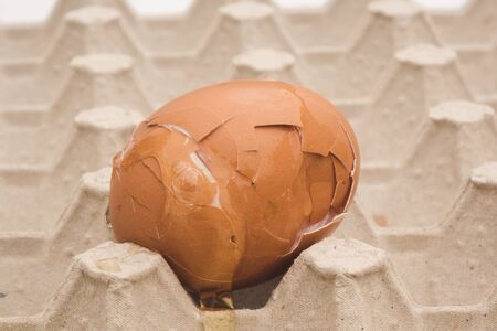 Carton packaging for eggs with broken eggshell on a white background.