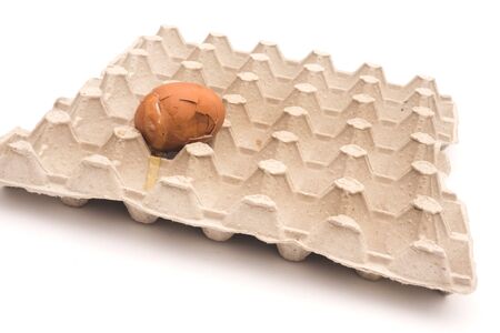 Carton packaging for eggs with broken eggshell on a light background.の写真素材