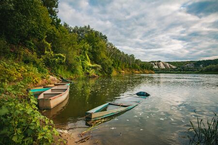 Old fishing boat near wooden jetty. Beautiful russian landscape. Sunset reflection in the water.の写真素材