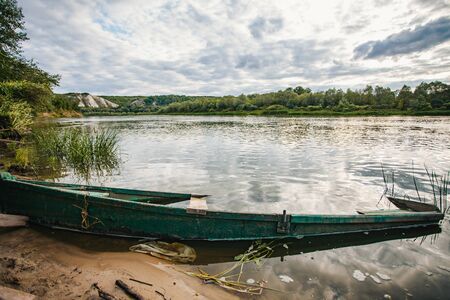 abandoned old wooden fishing boat near pier in summer lake or river. beautiful summer sunny day or evening. forsaken boat. russian nature.の写真素材