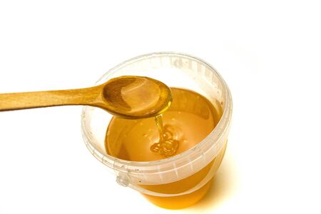 glass jar full of honey and dipper isolated on white background.の写真素材