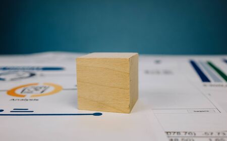 template in the form of a wooden cube lying on a stack of documents on a blue background.の写真素材