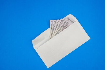 a wad of money in a white envelope on a blue background.