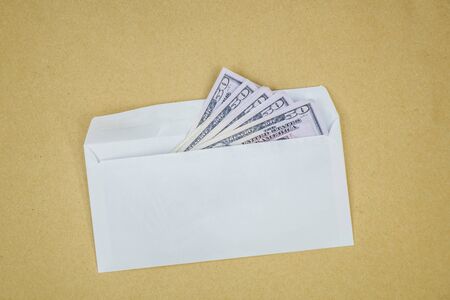 Stack of dollars in open envelope on brown background. Concept of corruption, illegal profit,...