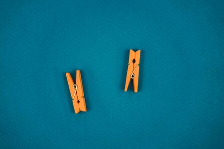 two orange clothespin isolated on blue background.