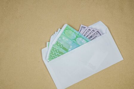 Stack of dollars in open envelope on brown background. Concept of corruption, illegal profit,...