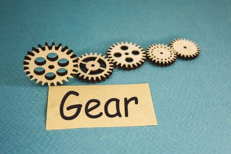 wooden gears lying on a blue background and the inscription gear.の写真素材