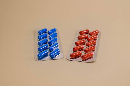 two packages of red and blue tablets on a beige background.の写真素材