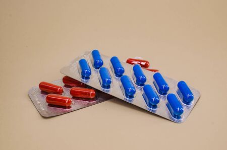 a blue pack of pills lies on a red pack of pills on a beige background.の写真素材