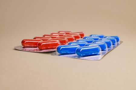 red and blue pill boxes on beige background.の写真素材