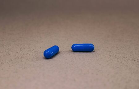 two blue capsule pills lie not far from each other.