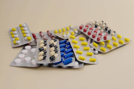 a bunch of pills and vitamins in packages lying on a beige background.