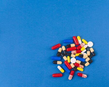 a pile of colorful pills and capsules lying in a pile on a blue background