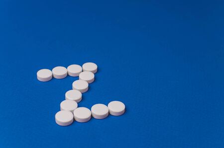 Letter Z made from white pills on a blue background.の写真素材
