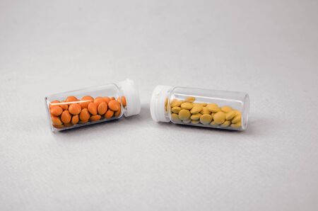 two glass packages with yellow and orange tablets lying with each other. black and white photoの写真素材