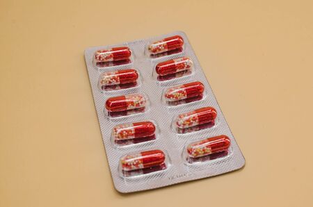 pack of capsule tablets red and white on a beige background