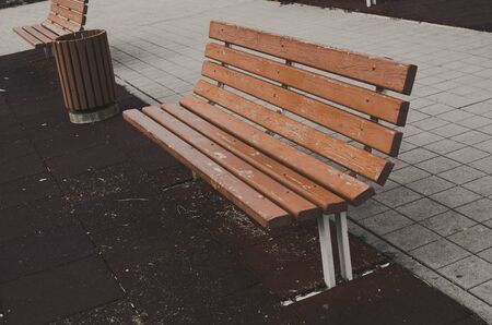 wooden bench in the park with a garbage can.の写真素材