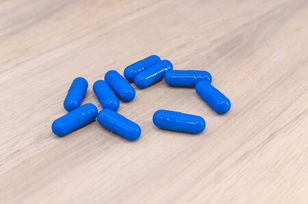 pile of blue pills on a wooden table