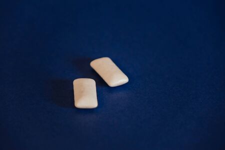 two white chewing gums on a blue backgroundの写真素材