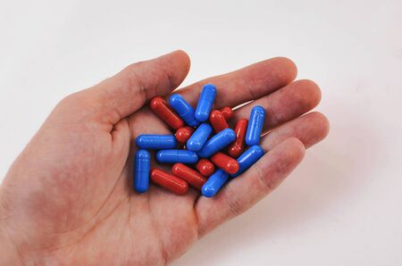 pile of tablets of red and blue in the mans hand on a white background